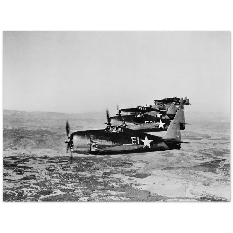 Aerial view of seven Grumman Hellcat airplanes in flight.
